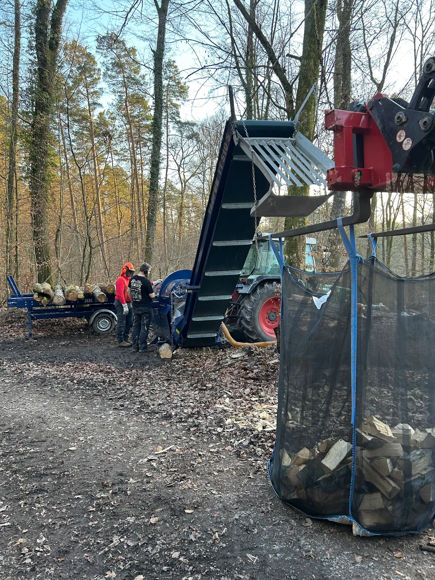 Mitarbeiter am Sägespaltautomat bei der Brennholzherstellung